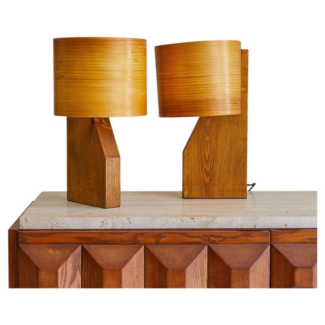 One available. A French table lamp from the 1960s, its sculpted wooden base rising in an angular profile to support a...