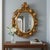 This eclectic mirror from the late 19th century is made of carved, gilded wood and decorated with faux marble paintings....