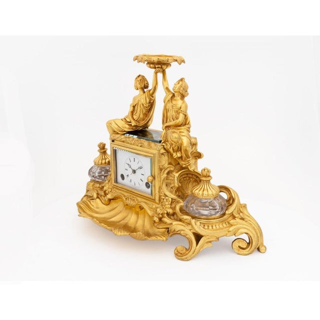 A refined gilded bronze desk clock, designed as an elegant writing accessory in the quintessential Napoleon III style. Two...