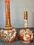 (2) Beautiful porcelain vases with hand painted detail in a red and gold coloration. Marked to underside. Small vase-...