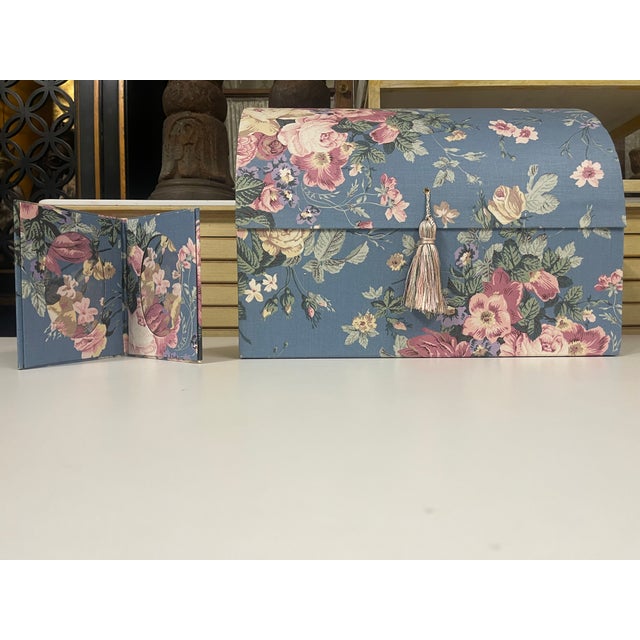 A vintage fabric-covered jewelry box with a domed, trunk-like lid, tasseled cord in a soft pink-and-gold twist, and...