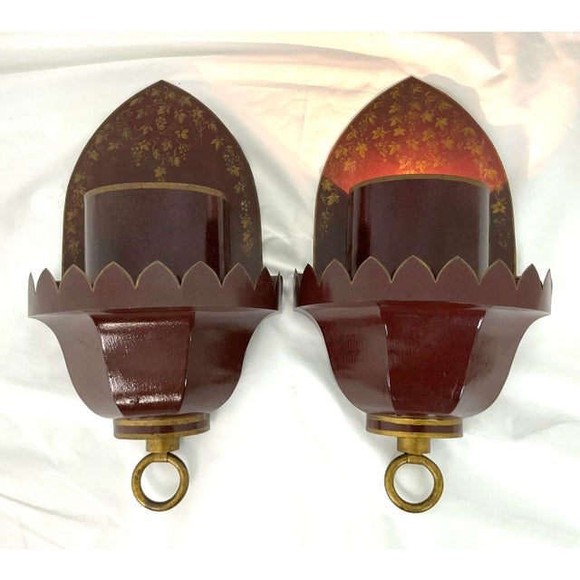 This elegant pair of wall sconces is crafted in richly lacquered burgundy tole, accented with fine hand-painted gilt...