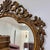A striking vintage wall mirror with an ornate, openwork crest, scrolling floral details, and a warm two-tone finish. Its...