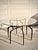 Sculptural Cyrano dining table by Made Goods featuring an organically formed bronzed iron base and thick round glass top....