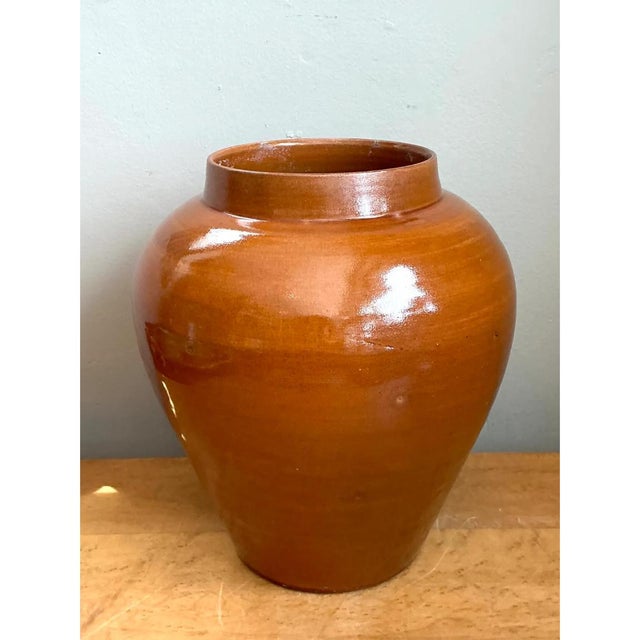 This vase presents a classic, full-bodied silhouette rooted in traditional North African pottery, its rounded shoulder...