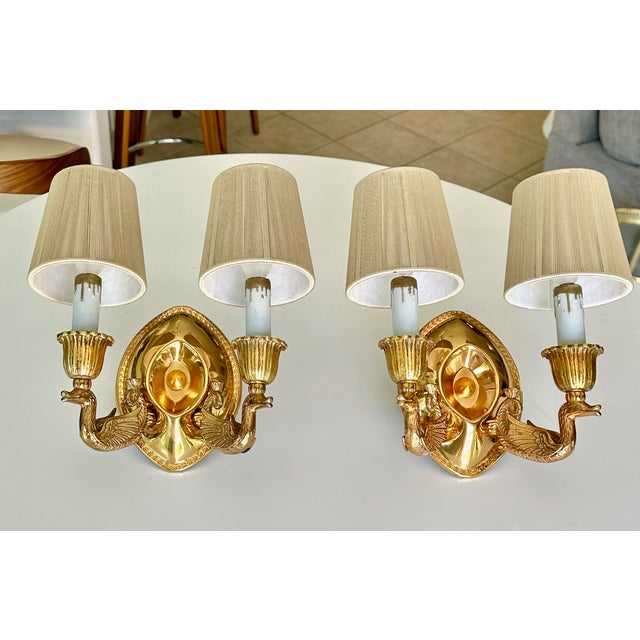 Pair of French Empire style brass sconces with 2 lights, featuring a swan motif. The brass lacquered finish is in great...
