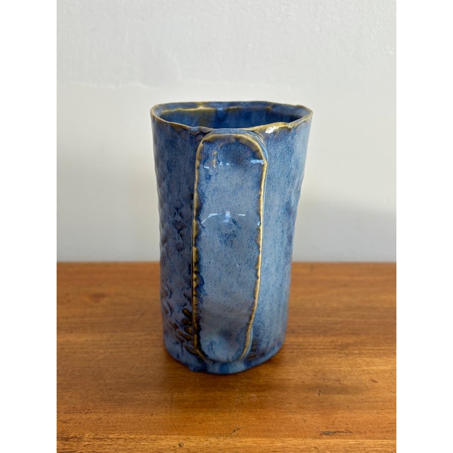Handmade blue pottery mug, with a folk art style and a pattern reminiscent of fish scales. Signed by maker. Most items...