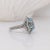 This statement ring features a brilliant blue oval aquamarine encased in a halo of natural earth mined diamonds. Made in...