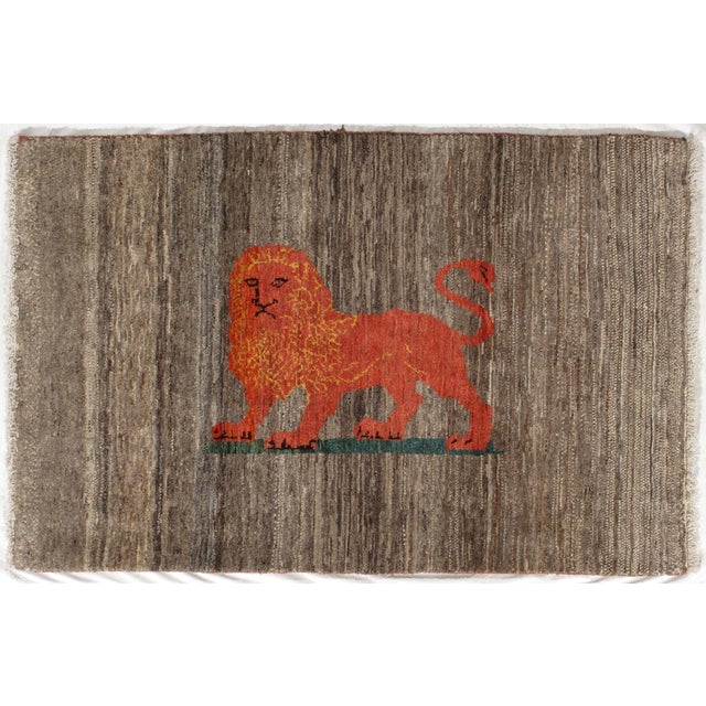 Vintage Persian hand-knotted Lori Gabbeh wool rug featuring a striking stylized lion motif set against a textured brown...