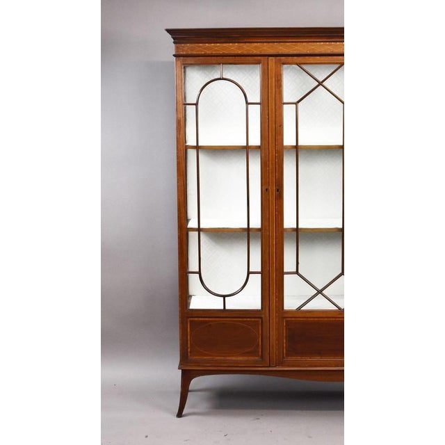 A fine Edwardian mahogany inlaid display cabinet of elegant proportions, featuring three glazed doors with decorative...
