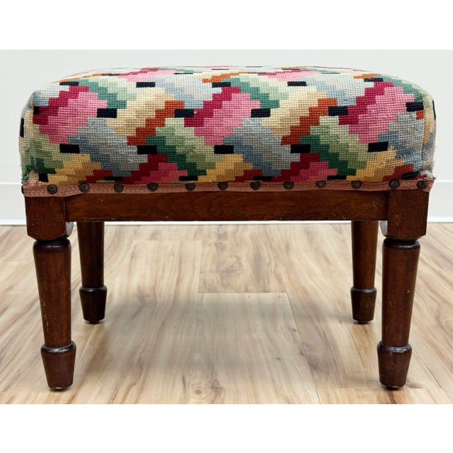 Vintage wood frame footstool with colorful patterned needlepoint upholstery to cushioned top. Ric rac edge secured with...