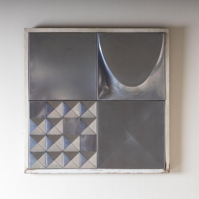 Set of two square wall panels, each composed of four metal tiles featuring various geometric and abstract relief designs....