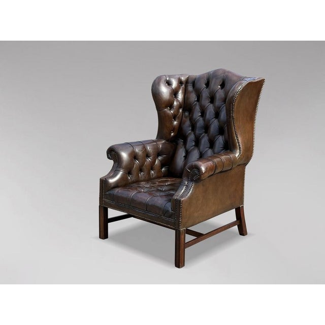A high-quality, early 20th-century Edwardian period brown leather full-button wing armchair in the George III style. The...