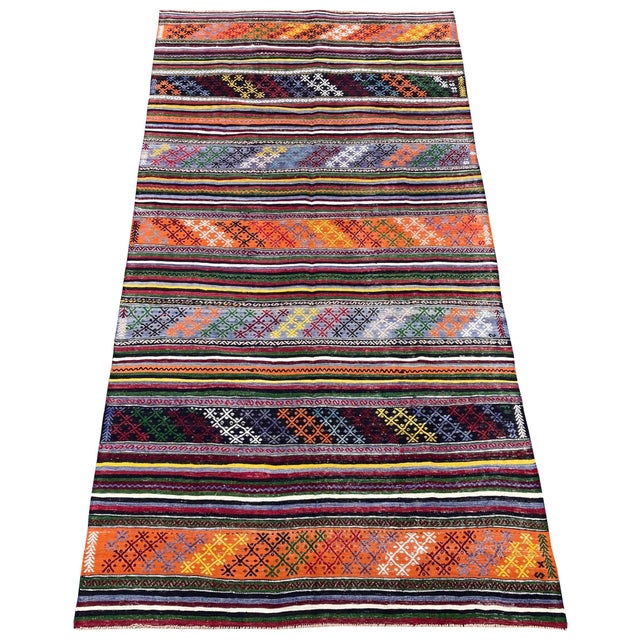 A lovely vintage kilim, handwoven in central Turkey circa 1960 with a banded design in blues, reds and golds. Size: 3.10m...