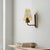 A vintage mid-century wall sconce featuring a warm amber and clear glass shade with a distinctive geometric etched or...