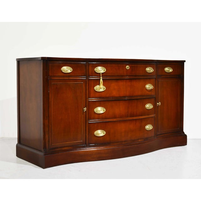 This is a classic Mid Century Hepplewhite Style Mahogany Sideboard Buffet by Bassett Furniture. Crafted from high-quality...