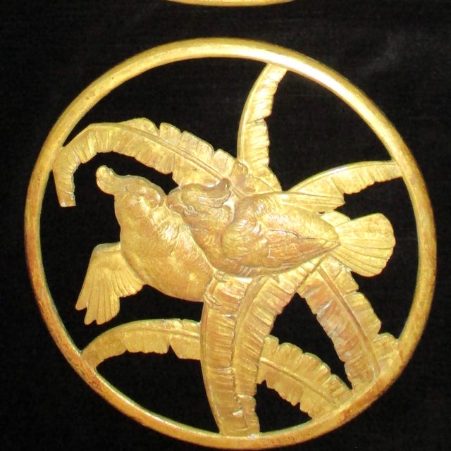 A pair of furniture or door mounts in a Tropical Deco manner. Gilt bronzes of two cockatoo's nuzzling each other on palm...