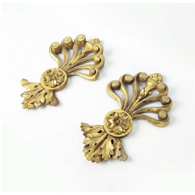 A pair of decorative early C19th gilt wood appliqués. This piece is attributed to the mentioned designer/maker. It has no...