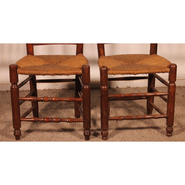 Two 19th-century oak straw-seated chairs Model with a "gendarme's hat" back, featuring four decorative panels in the...