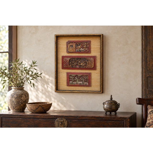 Three carved panels in red and gilt, framed together over a natural grasscloth ground. The carving is figural and finely...