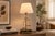 Table lamp dating to the 1950s, built around a brass balance-scale motif. Two suspended pans hang from the scale beam...