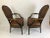 Impressive glamorous pair of roomy brown leather arm chairs having regal ebonized and gilded frames. The backs are oval...