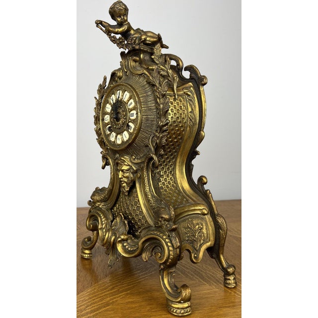 A highly decorative Vintage brass clock with an elegant ornate form and striking cherub detail to the top. Rich in...