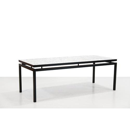 Elegant coffee table with a sleek black metal base and a characteristic floating tabletop inlaid with a delicate mosaic of...