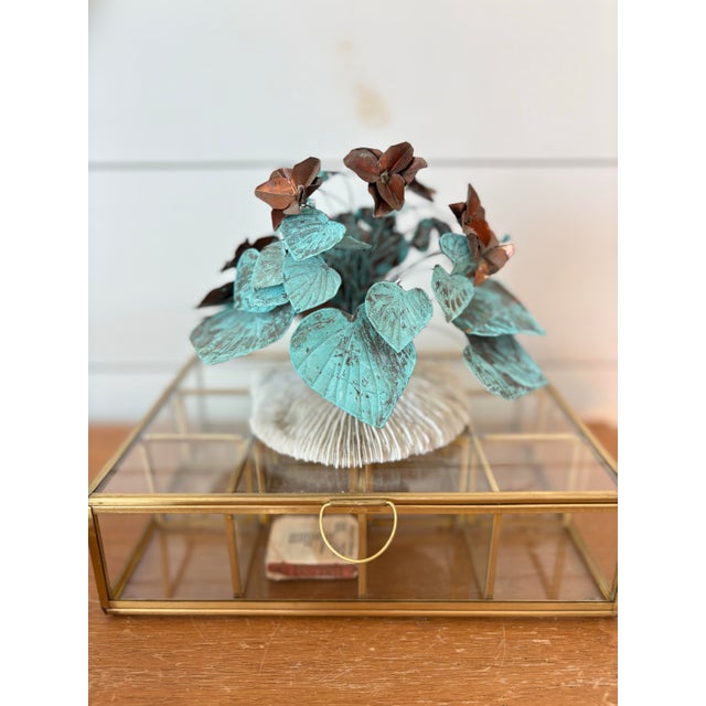 A striking vintage metal floral sculpture featuring beautifully aged verdigris leaves paired with warm copper-toned...