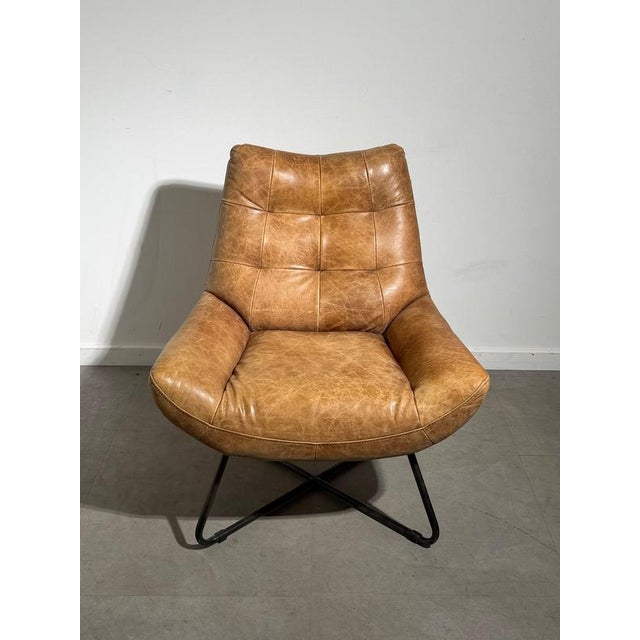 Inviting armchair upholstered in warm cognac leather, paired with a black metal base for an industrial look. Its generous...