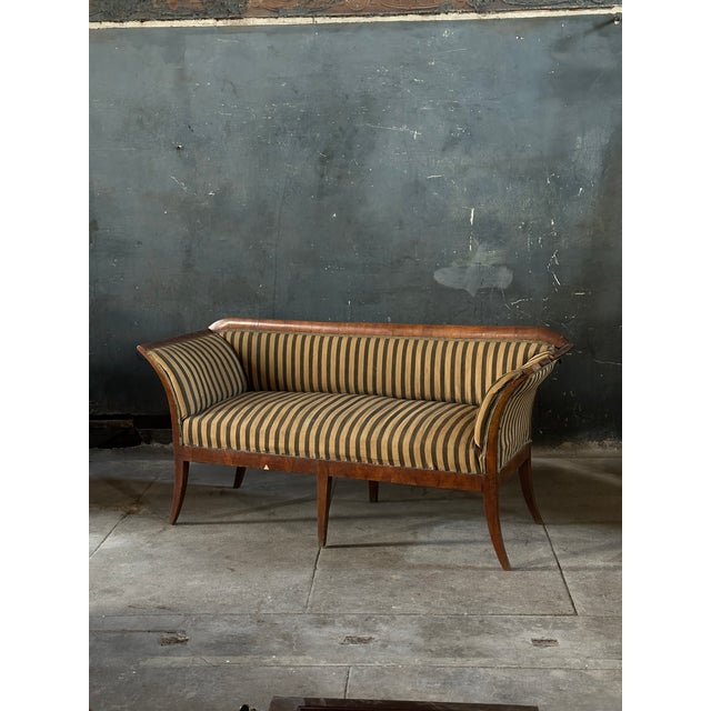 An elegant and simple period walnut Biedermeier settee. The classical design features elegant curved legs and arms in a...