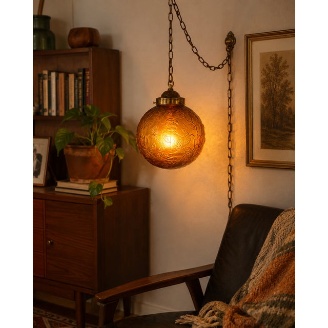 A striking vintage amber glass swag lamp dating to the 1970s era, featuring a beautifully embossed floral pattern across...