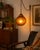 A striking vintage amber glass swag lamp dating to the 1970s era, featuring a beautifully embossed floral pattern across...