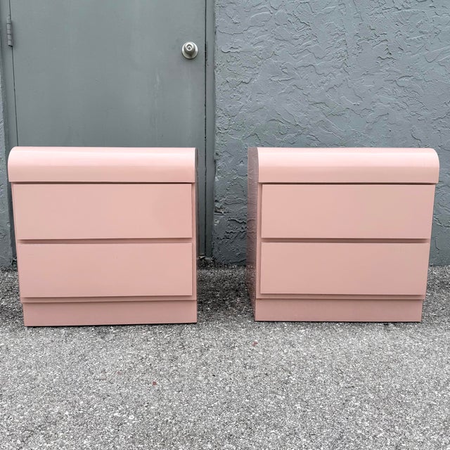 A striking pair of Postmodern waterfall nightstands finished in a soft blush pink gloss laminate, embodying the playful...