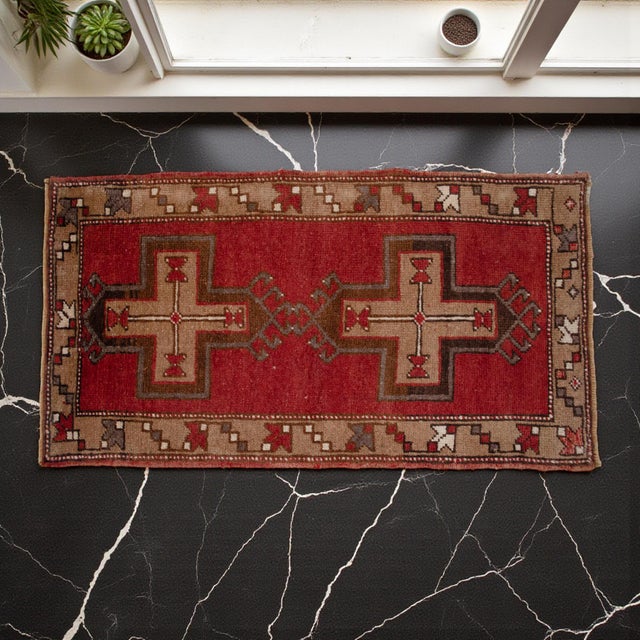 This striking vintage Oushak mat immediately draws the eye with its vibrant red field and bold geometric cross motifs....