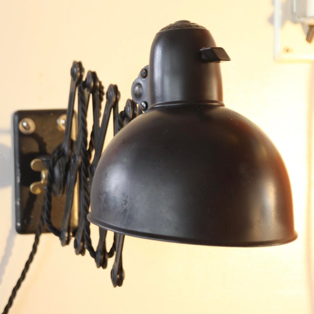This highly functional scissor wall lamp, designed by Bauhaus master Christian Dell for the lighting company Kaiser, is...