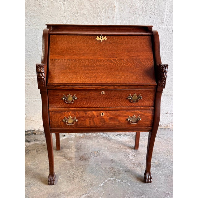 Antique oak desk with north wind face, two drawers, fitted interior with multiple shelves, large writing surface and claw...
