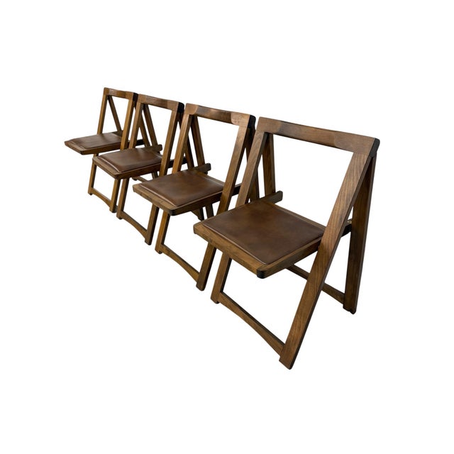 Bring versatile Mid-Century Modern style to your dining or entertaining space with this set of four vintage walnut folding...
