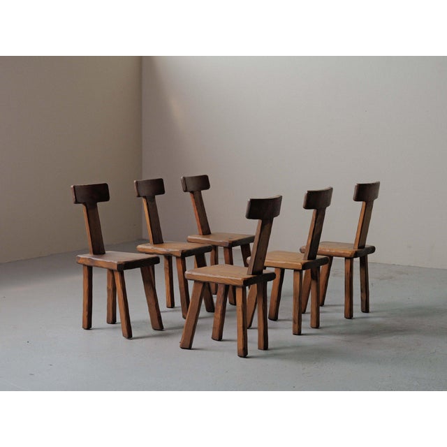 Set of six solid chestnut chairs handcrafted in France during the 1970s, It embodies a deliberately primitive and...