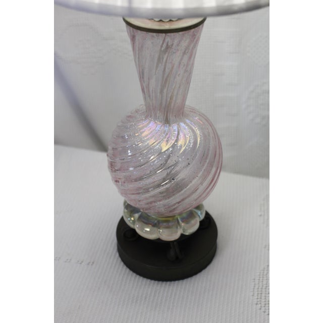A Murano glass lamp made by Barovier Toso. Glitter swirl glass in a light pink capped with darkened brass accents. The...