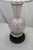 A Murano glass lamp made by Barovier Toso. Glitter swirl glass in a light pink capped with darkened brass accents. The...