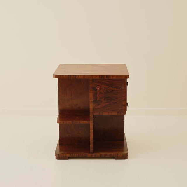 Swedish Art deco side table from the 1940's in richly figured wood veneer. The square-form cabinet is raised on a stepped...