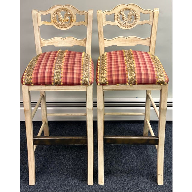 Pair of French Country style wooden barstools featuring a distressed white or cream finish, ladder-back design, with...
