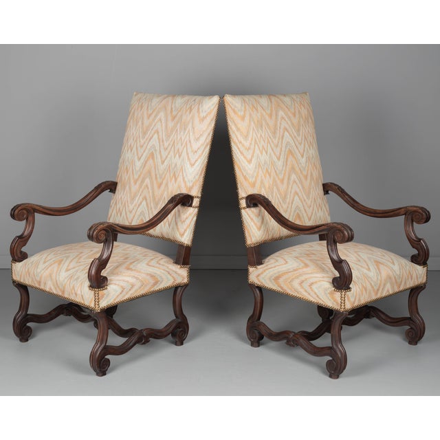 A pair of Louis XIV style fauteuils, or armchairs, made of walnut with carved details, sturdy construction and comfortable...