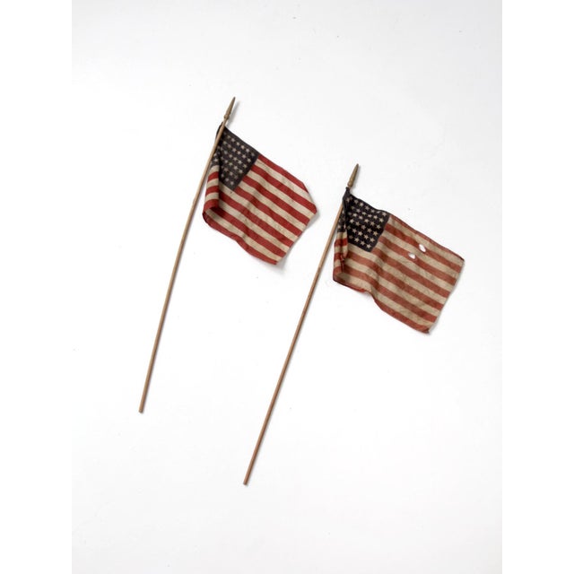 A pair of vintage 48 star parade flags with softly faded color and aged cotton construction. The turned wood staffs and...