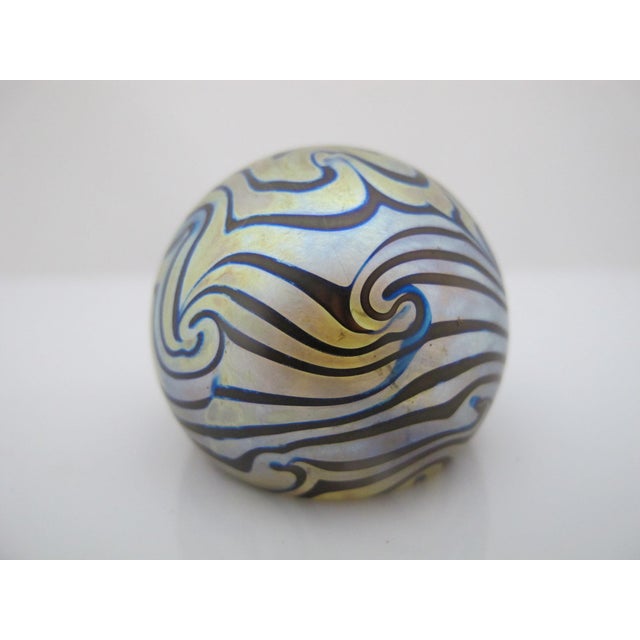 Vintage Robert Eickholt "King Tut" art glass paperweight, featuring sweeping, iridescent gold and blue-silver swirls over...