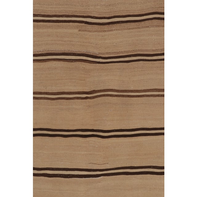 Handwoven in wool, this 4x8 contemporary Indian Rez Kilim runner features a warm beige field accented by fine brown linear...