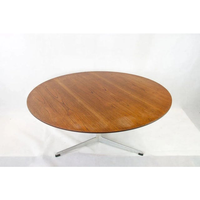 Teak coffee table on three legged aluminium base by Arne Jacobsen for Fritz Hansen. H 47 cm Diam 110 cm. This piece has an...