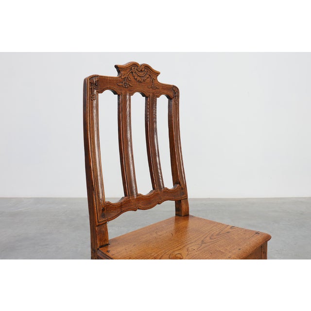 An elegant carved oak side chair from 18th‑century France, executed in the Régence style. The chair features a scrolled...