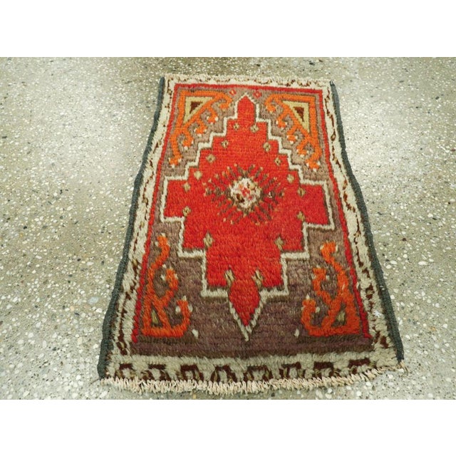 This Mid-20th century Turkish Anatolian rug, measuring 1' 2" x 1' 11", is a small yet striking example of the bold...